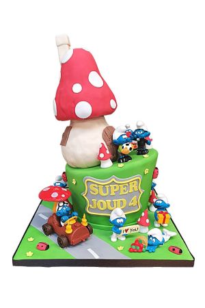 Un grand gâteau d'anniversaire vert sur le thème des Schtroumpfs, surmonté d'une imposante maison champignon rouge et blanche en pâte à sucre et de multiples figurines de Schtroumpfs.