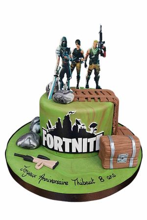 Exclusieve groene Fortnite verjaardagstaart gedecoreerd met game personages, een fondant buitkist, een wapen, een houten schans en het officiële logo, van The French Cake Company.