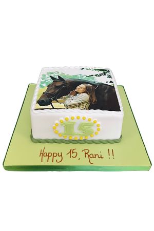 Gâteau d'anniversaire rectangulaire blanc personnalisé avec impression photo comestible d'une jeune fille enlaçant son cheval brun, sur plateau vert par The French Cake Company