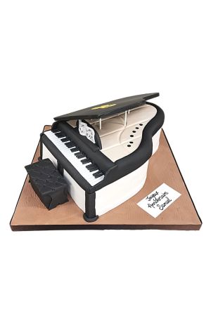 3D vleugelpiano verjaardagstaart met zwart-witte toetsen, bladmuziek en krukje gemaakt door The French Cake Company