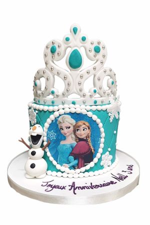 Gâteau d'anniversaire personnalisé bleu turquoise La Reine des Neiges orné de flocons blancs, d'une photo d'Elsa et Anna, de Olaf en 3D, d'effets matelassés et d'une splendide couronne, créé par The French Cake Company.