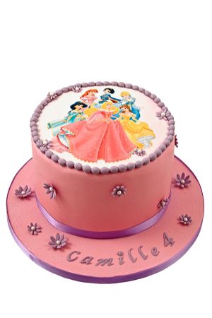 Een ronde roze fondant verjaardagstaart gedecoreerd met een ronde eetbare afbeelding van de Disney prinsessen, afgewerkt met paarse suikerparels en kleine bloempjes op een roze taartkarton met naam.