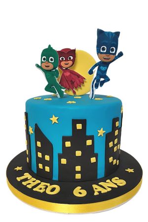 Un gâteau d'anniversaire bleu décoré d'une silhouette de ville noire et d'étoiles jaunes, surmonté des personnages Yoyo, Bibou et Gluglu.