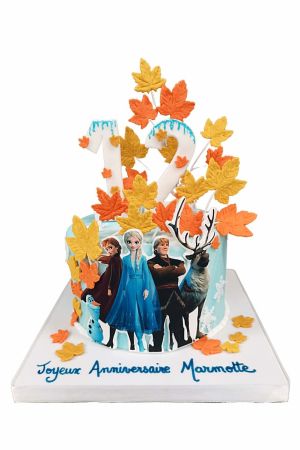 Gâteau d'anniversaire personnalisé bleu pastel sur le thème La Reine des Neiges 2 garni de feuilles d'automne orange et jaunes, d'effets de glace et des silhouettes d'Elsa, Anna, Kristoff, Sven et Olaf, créé par The French Cake Company.