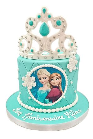 Gâteau d'anniversaire personnalisé bleu turquoise La Reine des Neiges orné de flocons blancs, d'une photo d'Elsa et Anna, d'effets matelassés et d'une splendide couronne, créé par The French Cake Company.
