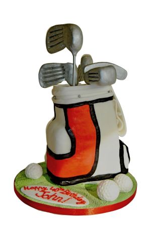 3D sculpted golf bag birthday cake filled with silver clubs and golf balls on green grass by The French Cake Company