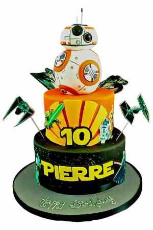 Un gâteau d'anniversaire à deux étages sur le thème Star Wars, noir et orange, avec une figurine 3D de BB-8 au sommet.