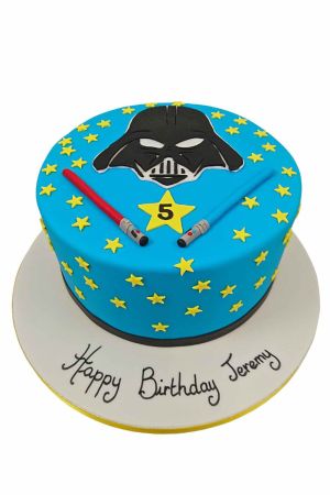 Un gâteau d'anniversaire rond bleu décoré avec le masque de Dark Vador, des sabres laser et des étoiles jaunes.