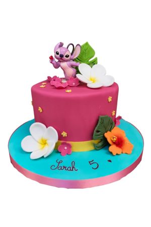 A bright pink and turquoise fondant birthday cake with a 3D Angel figure on top, decorated with white and orange tropical hibiscus flowers.