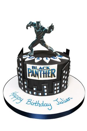 Round black birthday cake wrapped in a dark city skyline cutout, featuring a Black Panther movie logo, claw necklace tooth details, and a standing Black Panther superhero topper by The French Cake Company