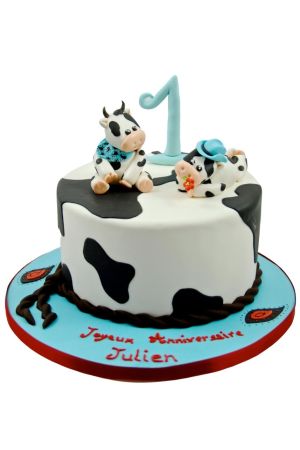 White and black cow print 1st birthday cake topped with two cute 3D sugar cows wearing a blue bandana and cowboy hat by The French Cake Company