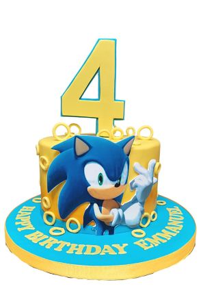 Un gâteau d'anniversaire jaune et bleu représentant Sonic le Hérisson, orné de nombreux anneaux dorés et d'un grand chiffre 4 jaune.