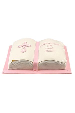 A communion cake sculpted into the shape of an open Bible with pink accents and a decorative pink cross on the left page.