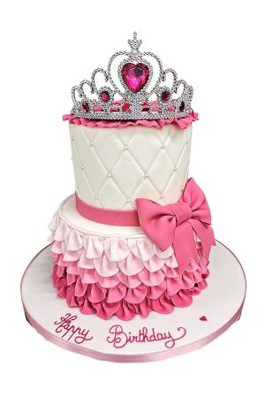 Two-tier pink and white princess birthday cake featuring ombre fondant ruffles, quilted ivory pattern with pearls, a large pink bow, and topped with a sparkling silver and pink jewel tiara, created by The French Cake Company.