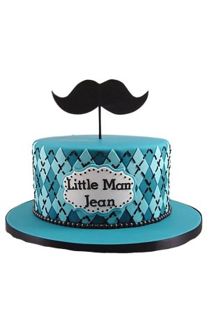 Gâteau bleu sarcelle à un étage avec des motifs de losanges et une décoration en forme de moustache noire au sommet.