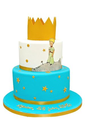 Gâteau de baptême à deux étages thème Le Petit Prince, avec une couronne dorée au sommet et des décorations d'étoiles.