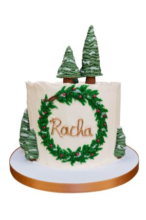 Gâteau de Noël blanc décoré de sapins et d'un nom personnalisé sur le devant