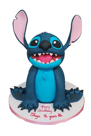 Un grand gâteau d'anniversaire sculpté en 3D représentant fidèlement le personnage Stitch de Disney, avec ses grandes oreilles et un large sourire.