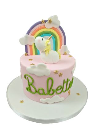 Exclusieve roze verjaardagstaart gedecoreerd met een kleurrijke regenboog, witte suikerwolken, gouden sterretjes en een ambachtelijk 3D eenhoorn figuurtje, van The French Cake Company.