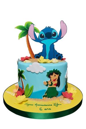 A light blue birthday cake with a large Stitch cutout zitting next to a palm tree on edible sand, with a hula-dancing Lilo on the side.