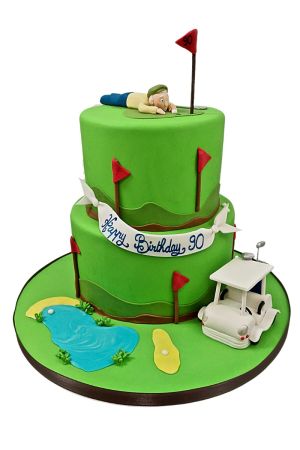 A two-tier golf-themed birthday cake with a golfer figurine on top.