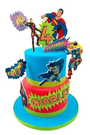 A two-tier red and blue birthday cake decorated with superhero cutouts, comic book "Kapow" bubbles, and a personalized name.