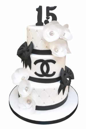 Somptueuse pièce montée d'anniversaire à trois étages blanche style Chanel avec nœuds noirs, logo CC, perles argentées et camélias en sucre nacrés réalisée par The French Cake Company