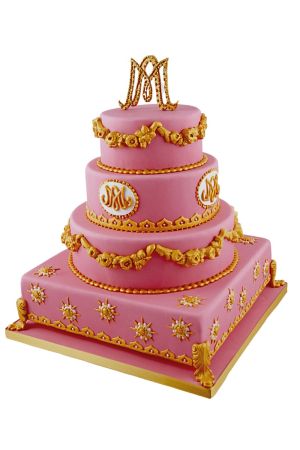 Une luxueuse pièce montée rose à quatre étages avec des niveaux carrés et ronds, décorée d'ornements dorés complexes et d'un monogramme personnalisé au sommet.
